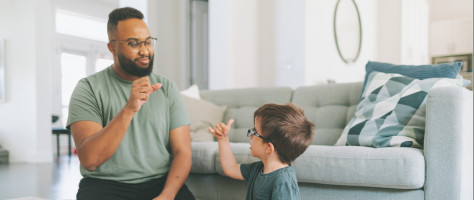 Eine erwachsene Person unterhält sich mit einem Kind durch Gebärden.