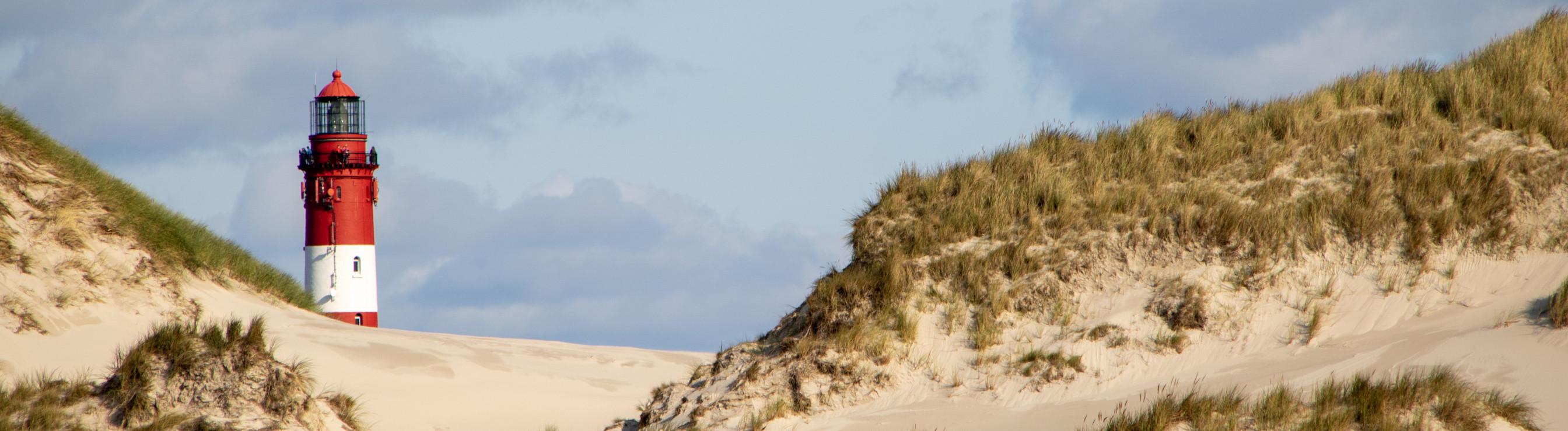 Ein roter Leuchtturm in einer Dünenlandschaft