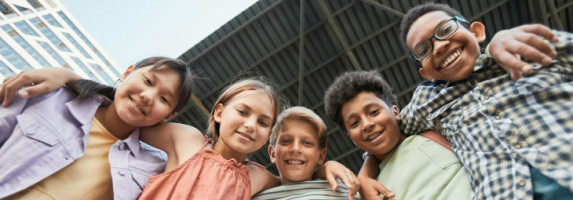 Fünf Jugendliche stehen in einer Reihe und haben die Arme umeinander gelegt.