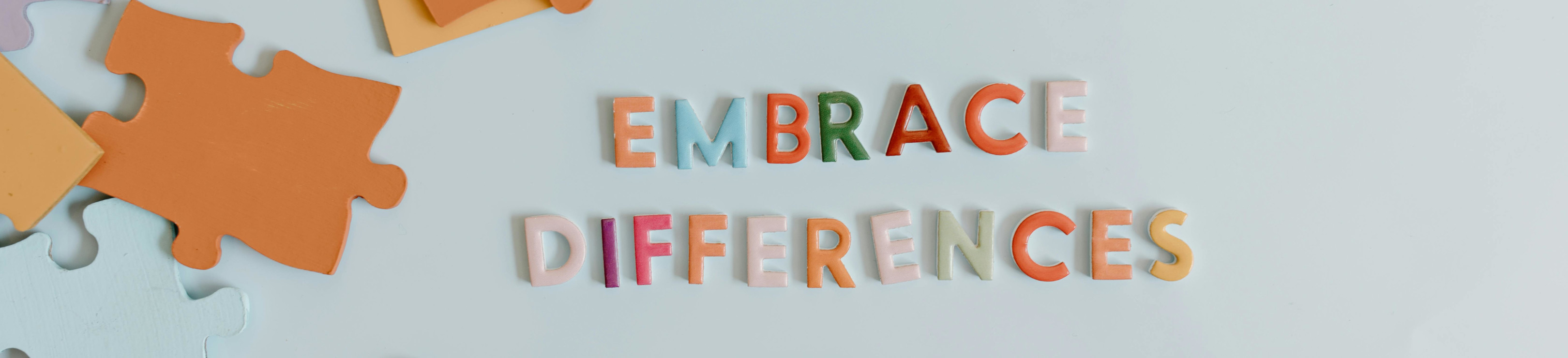 Links liegen bunte Puzzleteile mittig sind in bunten Buchstaben die Worte 