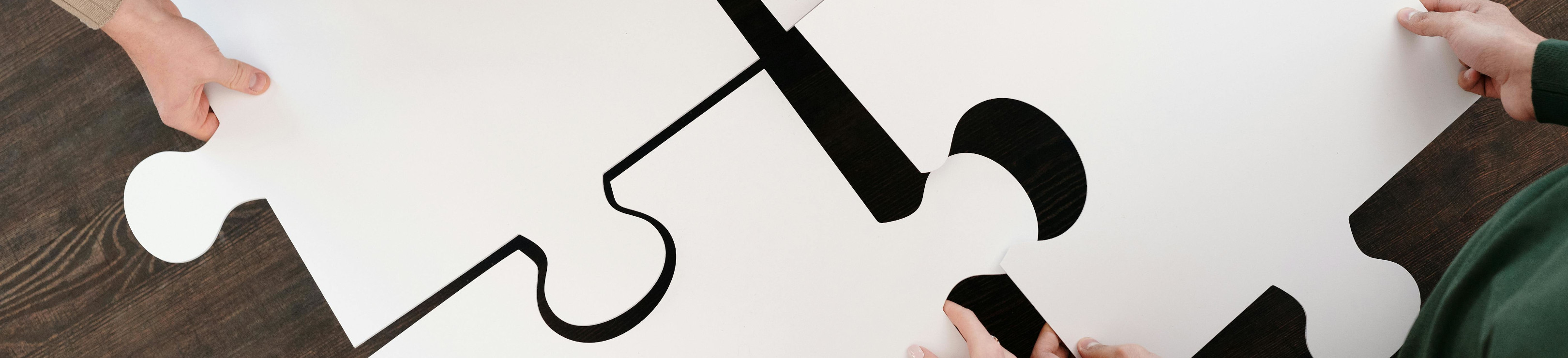 Menschen fügen übergroße Puzzleteile zusammen